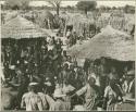 Group of people standing inside a kraal (print is a cropped image)