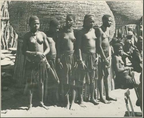 Five women standing next to a storage basket (print is a cropped image)