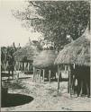 Storage baskets, two thatched roofs on poles (print is a cropped image)
