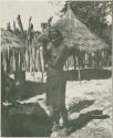 Woman standing, and another woman taking grain out of a basket (print is a cropped image)