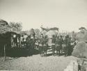 Group of people standing inside kraal (print is a cropped image)