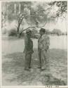Laurence Marshall and John Neser standing talking under a tree