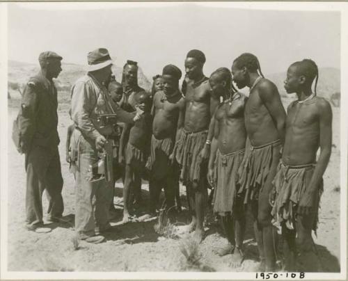 Group of people standing and listening to Laurence Marshall, who is holding a camera