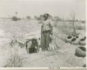 Man standing next to Laurence Marshall crawling out of a cave, with pottery on the ground next to them