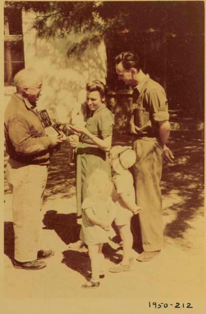 Laurence Marshall showing a Polaroid photograph to the Hartmann family at their farm