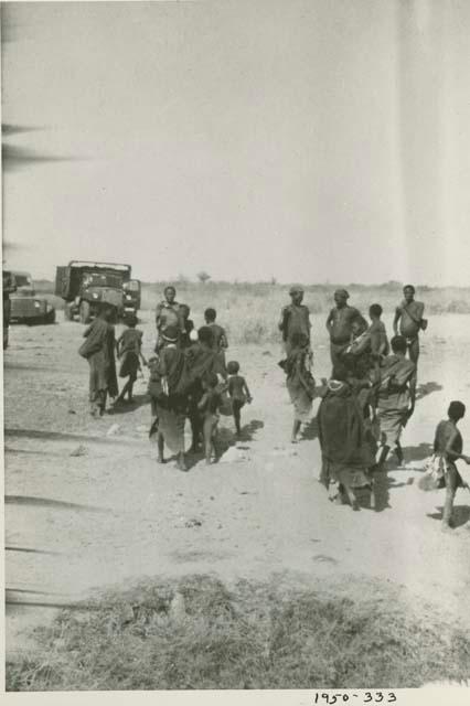 Group of people standing, with expedition trucks in the background