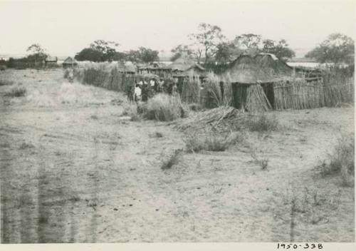 Group of people standing next to a fence surrounding a village