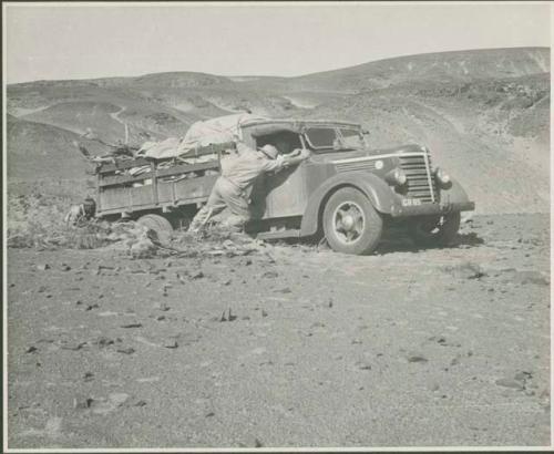 Expedition members pushing a truck out of the sand (print is a cropped image)