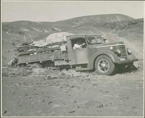 Expedition members pushing and driving a truck out of the sand (print is a cropped image)