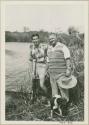 Assistant Manager of WNLA (Witwatersrand Native Labor Association) (left) standing with another man and a dog next to the Okavango River