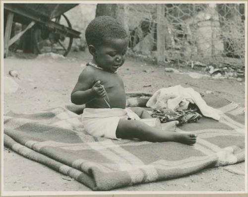 Lorna, Philip and Olga Hameva's baby sitting on a blanket