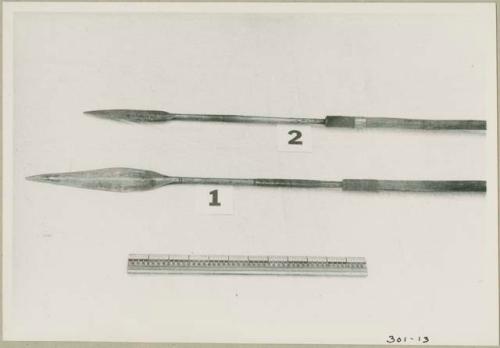 Two spear points and a ruler for measurement; one spear point is ornamented with horizontal lines