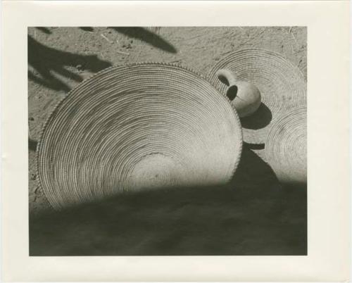 Three woven, winnowing baskets and a cracked gourd (print is a cropped image)