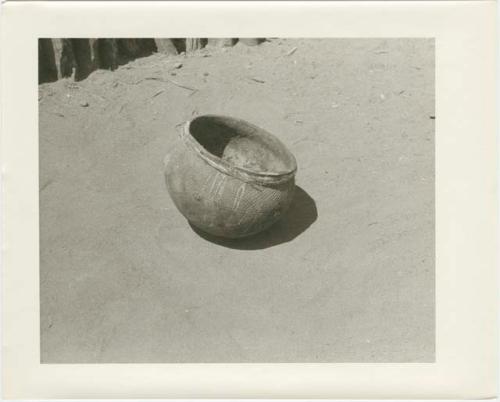 Round-bottomed pot with carrying thong around the rim; pot is ornamented with etched lines and rosettes (print is a cropped image)