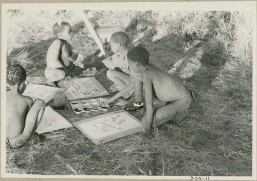 Four boys painting with Western materials, including /Gishay ("Old Gau's" son), with his foot bandaged, and Tsamgao (≠Toma's son), wearing a feather in his hair (print is a cropped image)