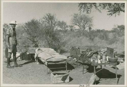 Claude McIntyre standing by his belongings in the expedition camp