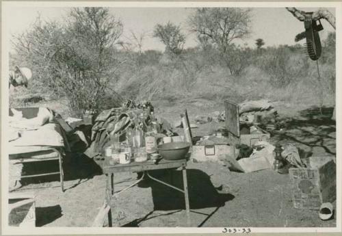 Claude McIntyre leaning over a cot next to his belongings in the expedition camp