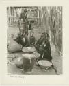 Four women working on grain; one woman is pounding in a mortar (print is a cropped image)