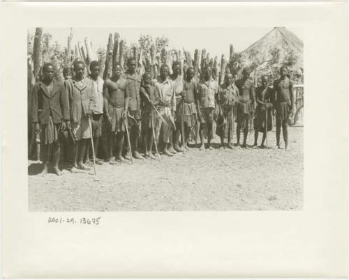 Men standing in a line including several men wearing Western clothing (print is a cropped image)