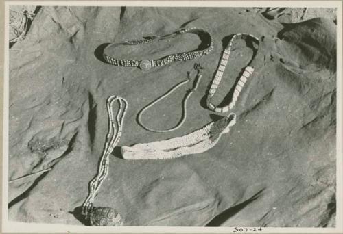 Two headbands, belt, tortoise shell, and strings of beads displayed on a kaross