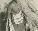 Woman standing, wearing an ornamented kaross and beaded apron, partial figure (print is a cropped image)