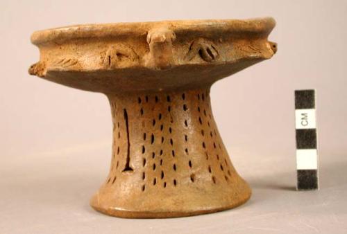 Unpainted pottery stand - bottom is incised and rattles, bird's heads in relief