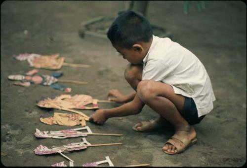 Child playing with paper wayang puppets