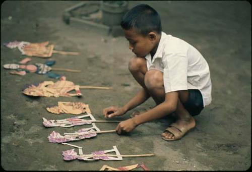 Child playing with paper wayang puppets