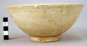 White ware bowl - ring base; greenish brown glaze; dots of clay in bottom