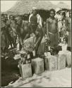 Women pouring grain from sack into tins (print is a cropped image)