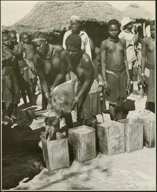 Women pouring grain from sack into tins (print is a cropped image)