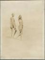 Two girls standing in the desert, one carrying water, near the Nile River