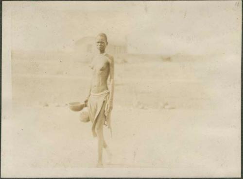 Girl standing in the desert holding a bowl, near the Nile River