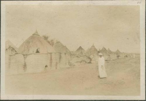 Man in white dress and turban walking through village, near the Nile River