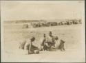 Dinka children sitting together, stacked wood in background used for Nile River steamer