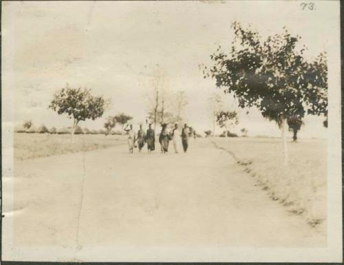 Women walking down wide street with baskets on their heads, Mongalla