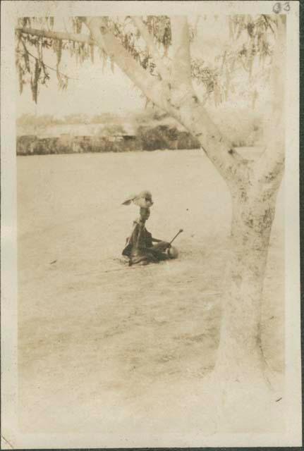 Individual sitting in the grass with basket on their head in Malakal, a British post