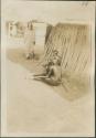 Man appearing to brush another's hair in the shade in Malakal, a British post