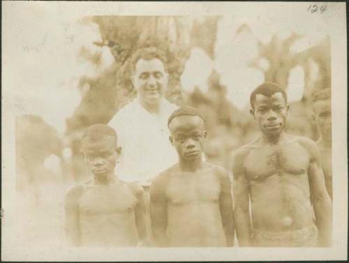 Two men (right) and two children (left) posing for photograph before a man in white shirt to demonstrate height