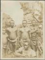 Pygmy men and young boys with non-Pygmy man squatting posing for photograph