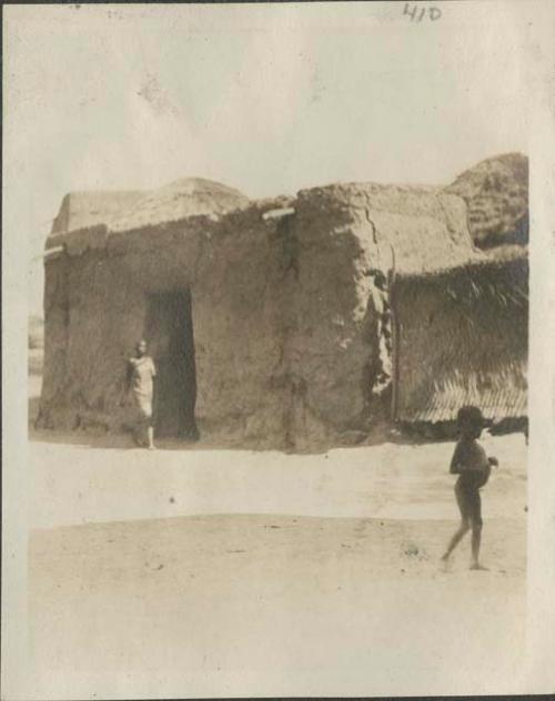 Thatched-roof huts and a child inside Goulfei