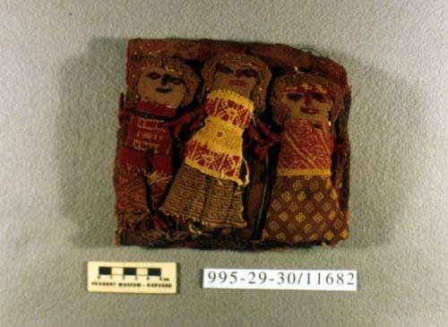 Three fabric dolls on rectangular stuffed base