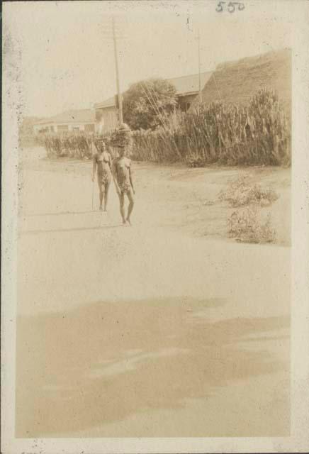 People on road, with fence and houses in background