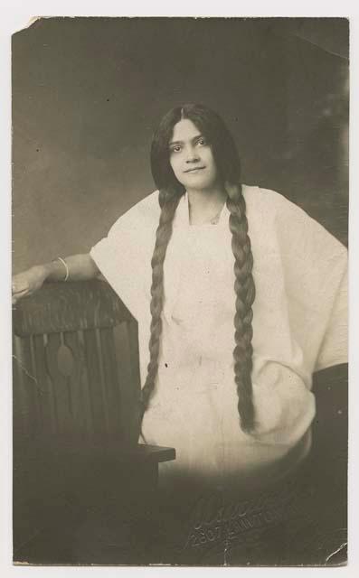 Portrait of a woman with very long braided hair, on a postcard.