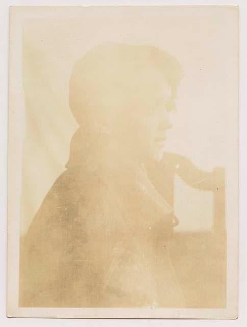 Photo of a woman sitting in a chair, very faded.