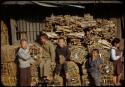Boys in front of stacks of firewood