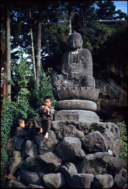 Two boys next to Buddha statue