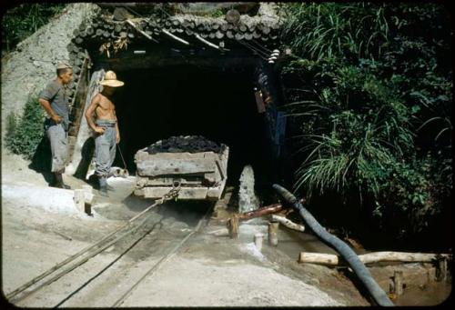 Two men standing at entrance to coal mine