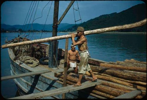 Men unloading lumber from boat on Kitakami River