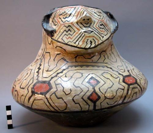 Human effigy pot, red clay, dark brown and orange on white glaze